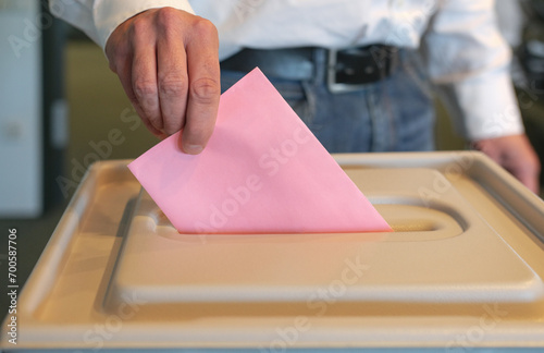 Stimmabgabe im Wahlbüro: Nahaufnahme der Hand eines Mannes, der seinen Stimmzettel in die Wahlurne steckt, viel Copy Space photo