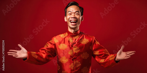 Asian man wearing traditional cheongsam qipao dress with gesture of congratulation isolated on red background. Happy Chinese new year. photo
