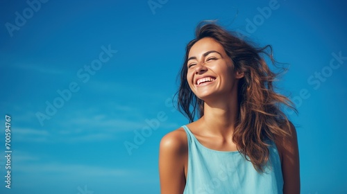 A beaming young woman standing against a deep azure background, her smile radiating warmth and positivity