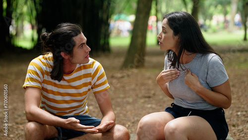Angry couple with relationship problems fighting outside sitting in a park bench. Young couple having argument. Married people in fight
