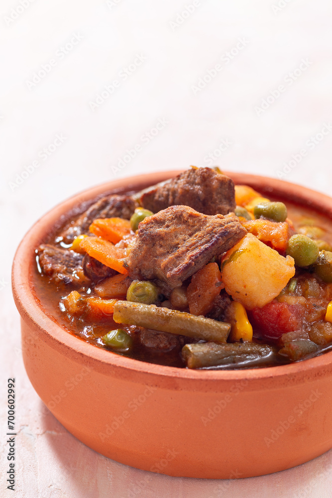 Delicious beef stew with potato, green beans, carrot, peas and corn, in ceramic bowl, vertical Delicious beef stew with potato, green beans, carrot, peas and corn, in ceramic bowl, vertical