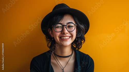 Beautiful young woman, smiling, in hat and black clothes and wearing glasses.