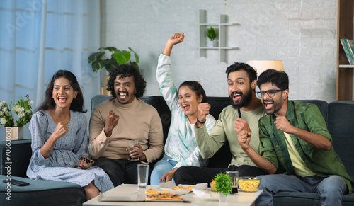 Group of young sport fan celebrating win while watching live cricket match on television at home - concept of weekend entertainment, championship and friendship. photo
