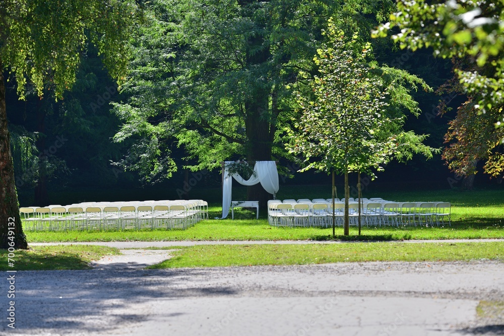 Modern wedding in a garden park and white decoration of the altar and chairs for guests