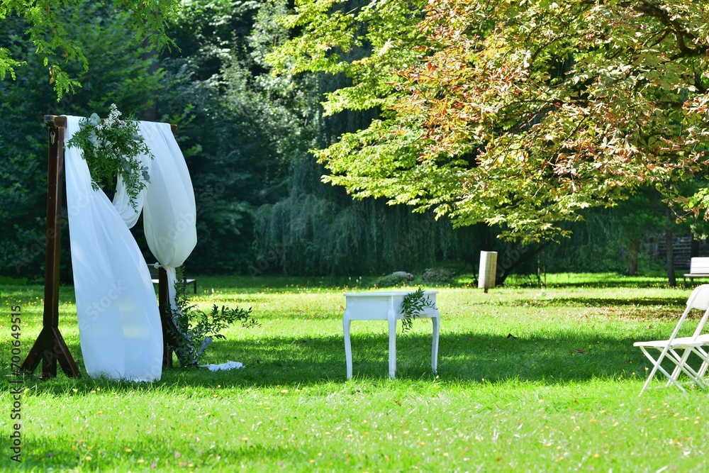 Decorated wedding altar at an outdoor wedding in a garden park with white chairs