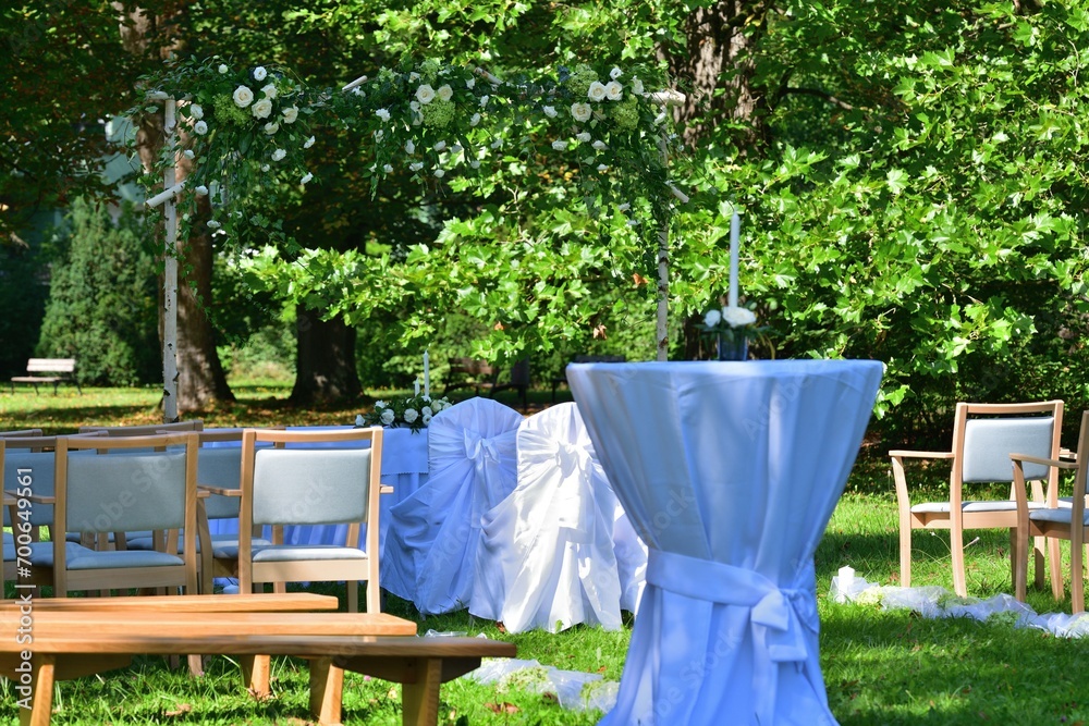 Decorated wedding altar at an outdoor wedding in a garden park with white chairs