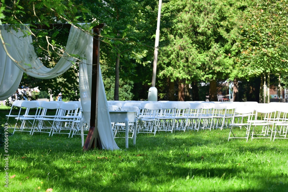 White decorated wedding chairs for guests in a garden park for a wedding