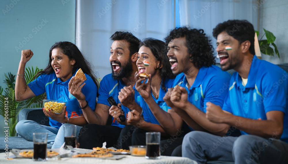 Group of excited Indian cricket fans celebrating by shouting for Team India win in cricket while watching tv at home - concept of cheering supporters, entertainment and championship match - obrazy, fototapety, plakaty 