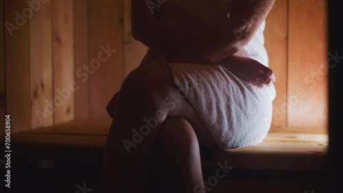 Woman sits on wooden bench in sauna photo