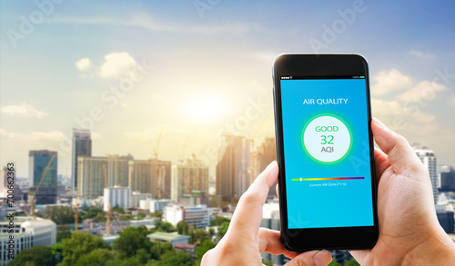 Air quality mobile app concept concept.close-up of man hands holding mobile phone on blurred cityscape as background