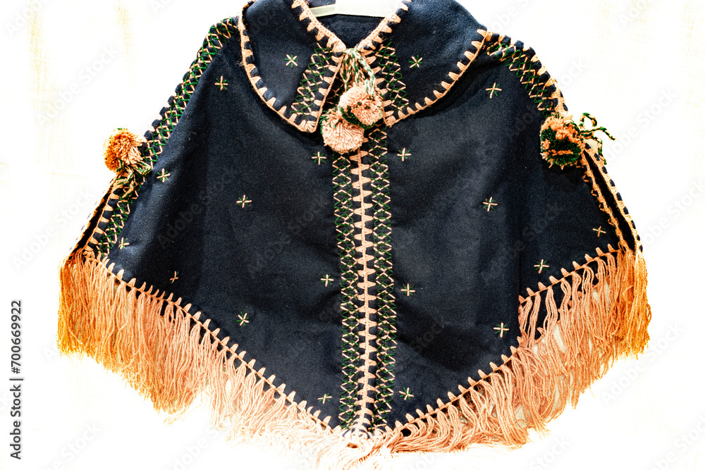 Traditional African warm clothing for women and girls, black colored sweater made of camel hair and wool with yarns hanging, stars and zigzag patterns in green and beige colored threads woven.