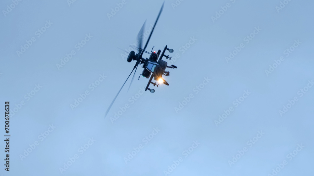 close-up of a British army Boeing Apache Attack helicopter gunship AH64E (AH-64E ArmyAir606) at full bank in a hammerhead stall turn, Wiltshire UK close-up of a British army Boeing Apache Attack helicopter gunship AH64E (AH-64E ArmyAir606) at full bank in a hammerhead stall turn, Wiltshire UK