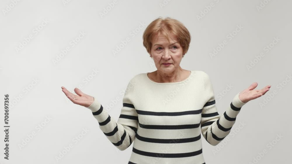 An elderly woman with a puzzled face and shocked gaze shrugs, turns a ...