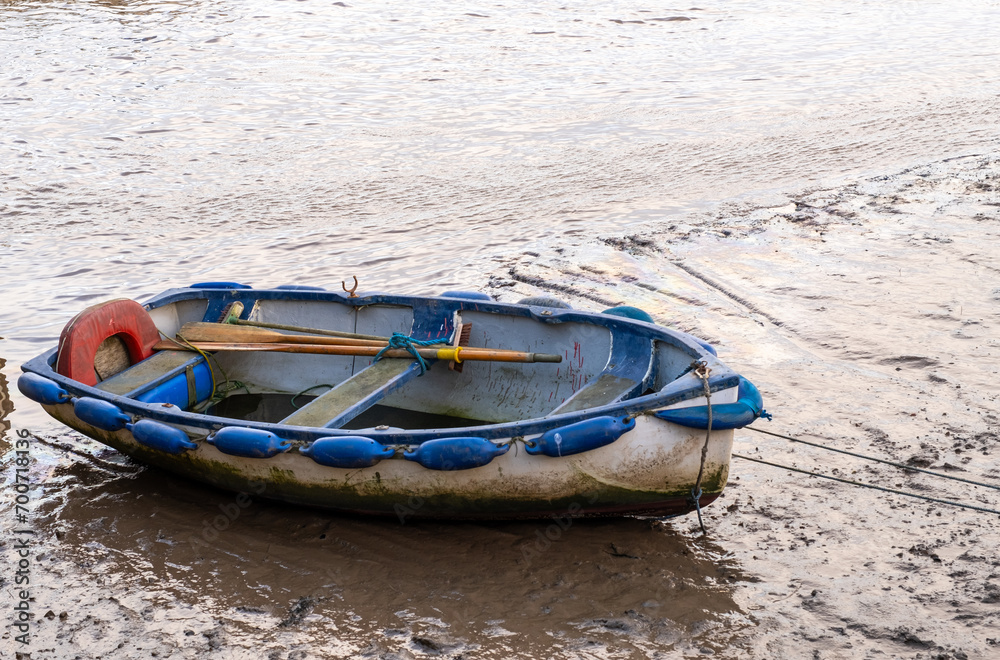 Wells-Next-The-sea, Norfolk, UK - December 29 2023. Small rowing boat beached in the harbour at low tide Wells-Next-The-sea, Norfolk, UK - December 29 2023. Small rowing boat beached in the harbour at low tide