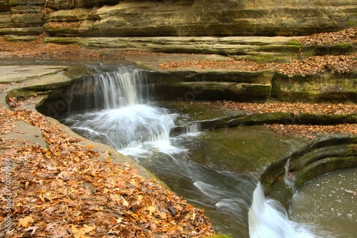 Closeup of a small, tiered waterfall surrounded by fallen brown leaves on a snowless Winter day at Matthiessen State Park, near Oglesby, Illinois. photo