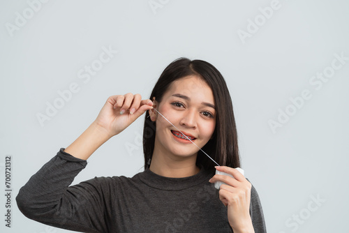 Asian woman braces using dental floss. Teeth braces on the white teeth of women to equalize the teeth. Bracket system in smiling mouth, close up photo teeth, macro shot, dentist health concept.