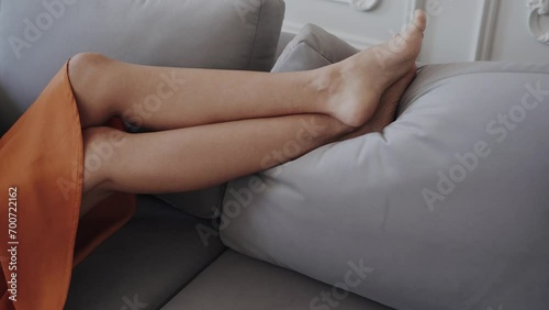 Crop view of woman legs while relaxing on comfortable couch with pillow photo