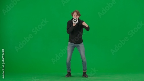 Male activist with raised fist shouting menacingly into megaphone in studio on green screen. Front view of a pro protest man. Protest action, fight for human rights, strike.
