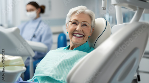 Elderly female patient with white hair  smiles happily while sitting in a dental chair