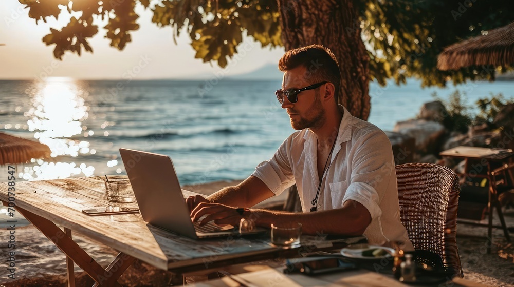 Man on seashore working remotely on computer