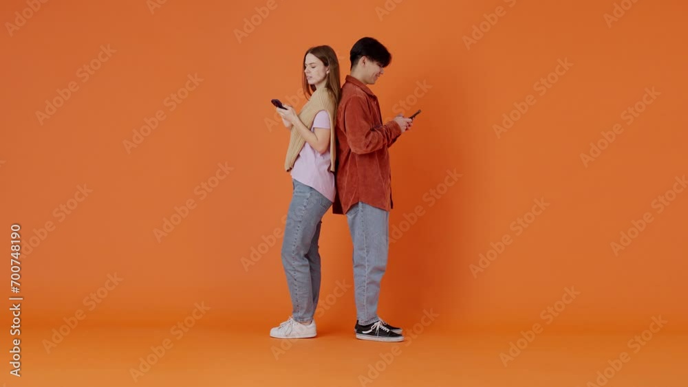 Woman and Asian man chatting peeking at screens in room Woman and Asian man chatting peeking at screens in room