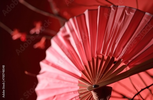 a pink origami fan hangs on a red background