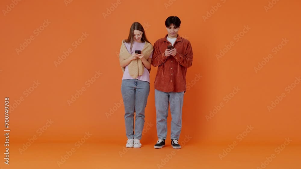 Smiling European lady and Asian guy chatting online on phones Smiling European lady and Asian guy chatting online on phones