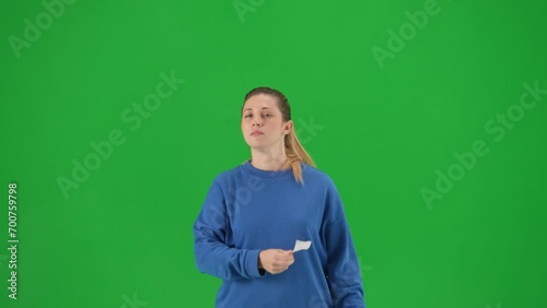 A woman with her mouth taped with black tape holds a poster with the inscription free speech. Protestant woman removing tape from her mouth on green screen close up.