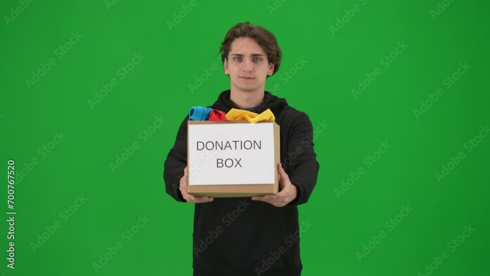 A man volunteer holds a box full of clothes labeled Donation box, close up. The man holds out the box and nods affirmatively on the green screen. Helping people. A man volunteer holds a box full of clothes labeled Donation box, close up. The man holds out the box and nods affirmatively on the green screen. Helping people.