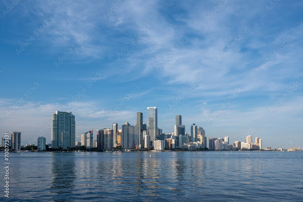 City of Miami, Florida skyline reflected in calm water of Biscayne Bay at sunset on clear sunny December afternoon.