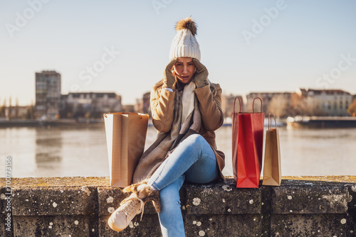 Fotografie Woman in warm clothing with shopping bags is worried because she spent too much money