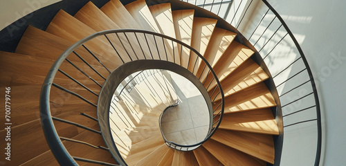 A modern minimalist spiral staircase, combining light-colored wood treads with simple, stylish ironwork on the sides.
