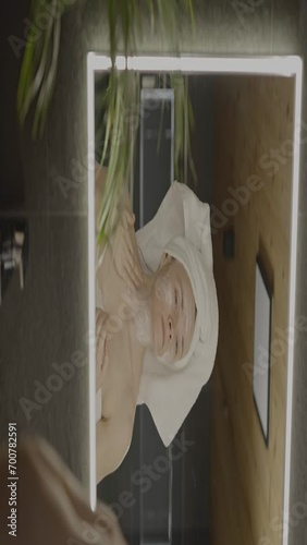 Caucasian female in her 40s is making her daily skin care routine