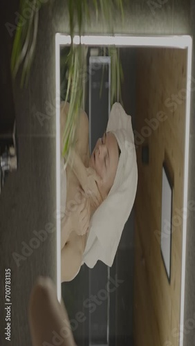 Caucasian female in her 40s is making her daily skin care routine