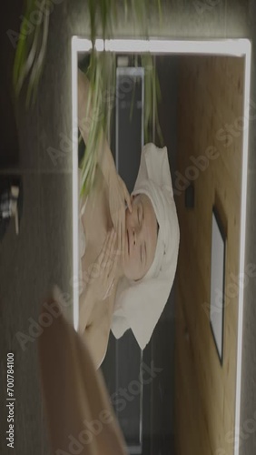 Caucasian female in her 40s is making her daily skin care routine