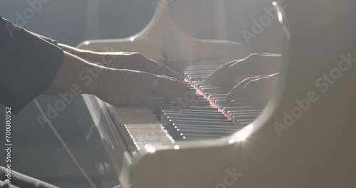 Male pianist plays grand piano in a music studio. Pianist plays beautiful grand piano, touches piano keys. Hands close-up, slow motion photo