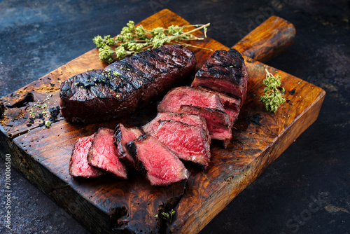 Barbecue dry aged angus roast beef steak with herb butter and dried oregano served as close-up on a rustic cutting board with copy space photo