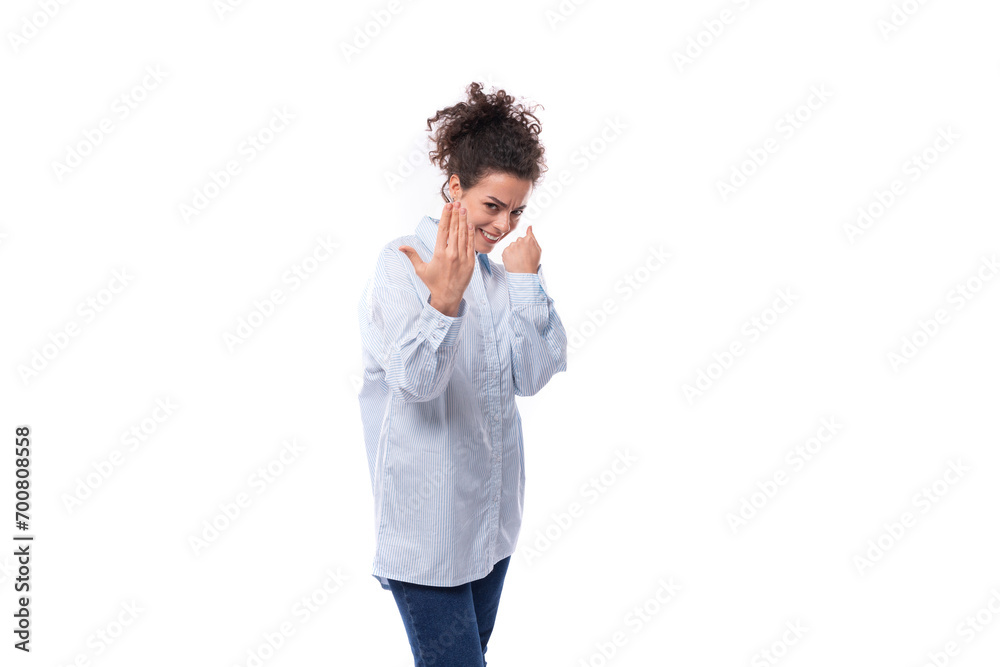 brunette curly young employee of a business company woman dressed in a light blue shirt on a white background with copy space brunette curly young employee of a business company woman dressed in a light blue shirt on a white background with copy space