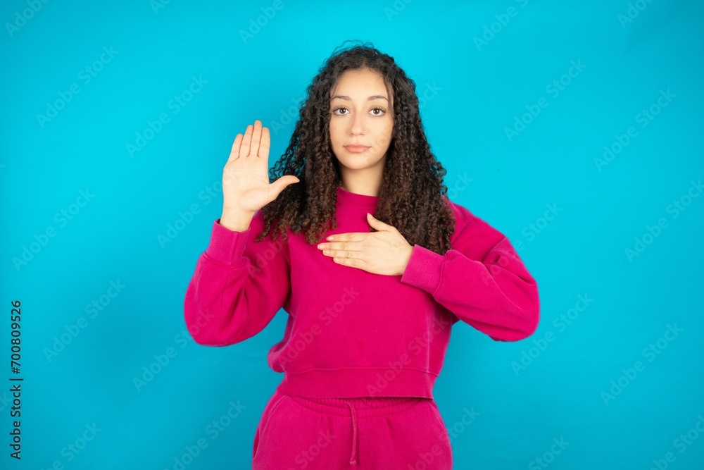 Fototapeta premium Young beautiful teen woman Swearing with hand on chest and open palm, making a loyalty promise oath