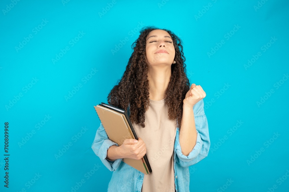 beautiful teen girl being excited for success with raised arms and closed eyes celebrating victory. Winner concept. beautiful teen girl being excited for success with raised arms and closed eyes celebrating victory. Winner concept.