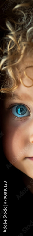 portrait of a four-year-old child with blond curly hair and bright blue eyes, looking through a thin slit portrait of a four-year-old child with blond curly hair and bright blue eyes, looking through a thin slit