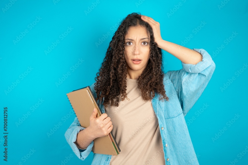 Embarrassed beautiful arab student carries notebooks with shocked expression, expresses great amazement, Puzzled model poses indoor Embarrassed beautiful arab student carries notebooks with shocked expression, expresses great amazement, Puzzled model poses indoor
