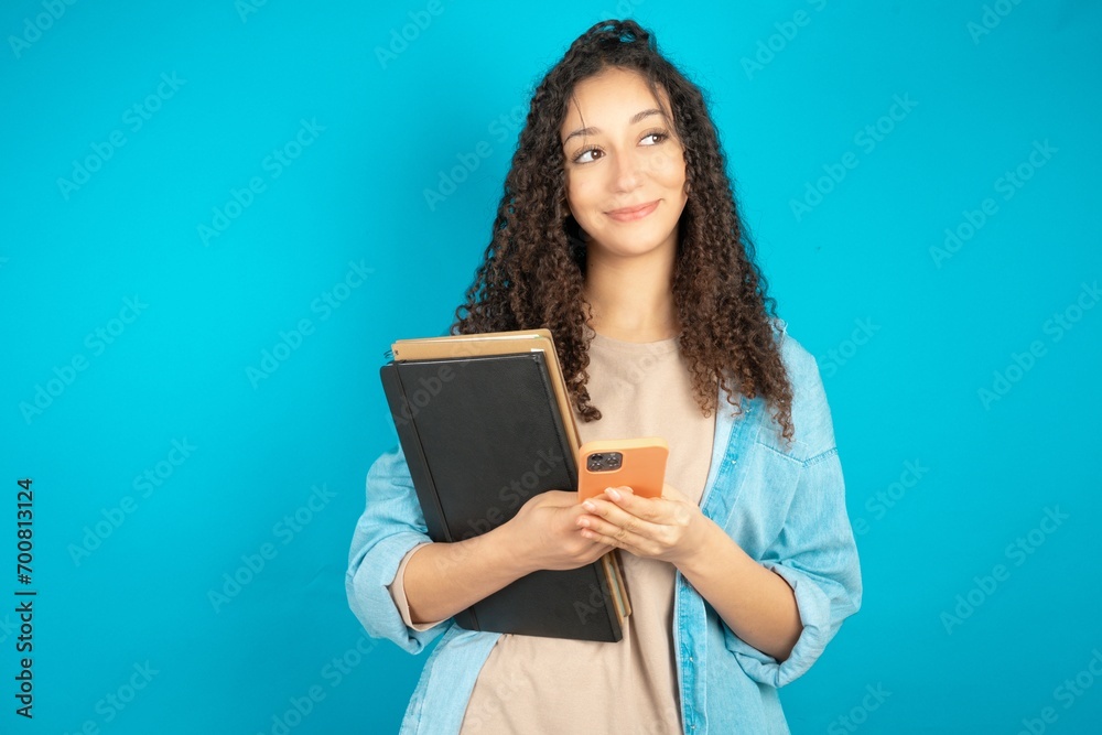 beautiful arab student carries notebooks hold telephone hands read good youth news look empty space advert beautiful arab student carries notebooks hold telephone hands read good youth news look empty space advert