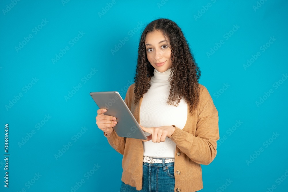 Photo of happy cheerful smart beautiful caucasian teen girl wearing brown sweater hold tablet browsing internet Photo of happy cheerful smart beautiful caucasian teen girl wearing brown sweater hold tablet browsing internet