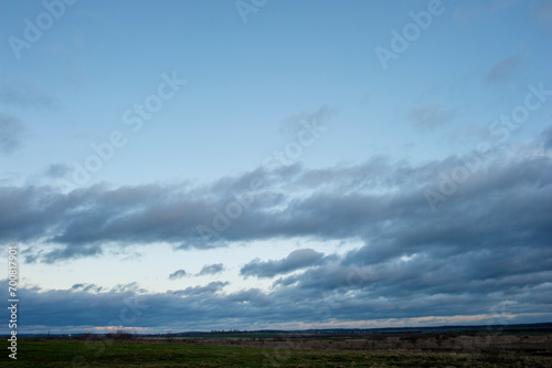 Panorama of dawn fire in the sky above the natural pasture. Golden red clouds just before sunrise. Picturesque landscape at sunrise. Beauty in nature