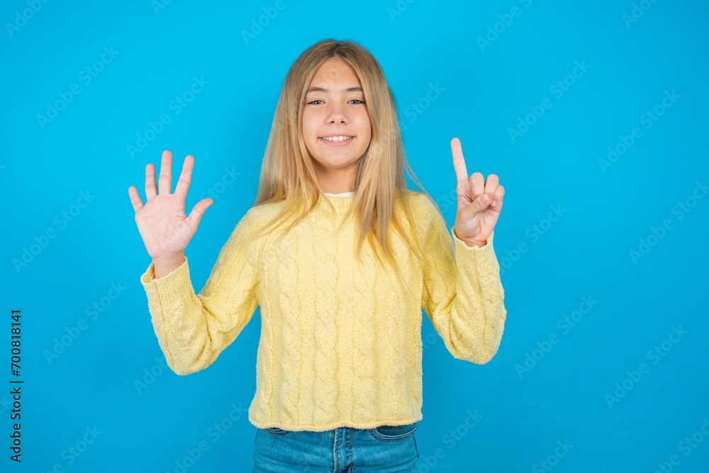Φωτογραφία Beautiful kid girl wearing yellow sweater holding notebook showing and pointing up with fingers number six while smiling confident and happy