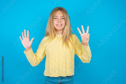 Beautiful kid girl wearing yellow sweater holding notebook showing and pointing up with fingers number eight while smiling confident and happy.