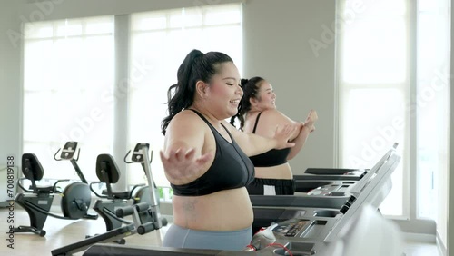 Two chubby women doing a stretching and little chat on a treadmill before start running. photo