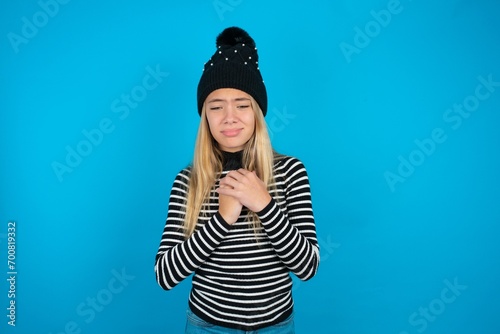 Sad Teen caucasian girl wearing striped sweater and woolly hat desperate and depressed with tears on her eyes suffering pain and depression in sadness facial expression and emotion concept