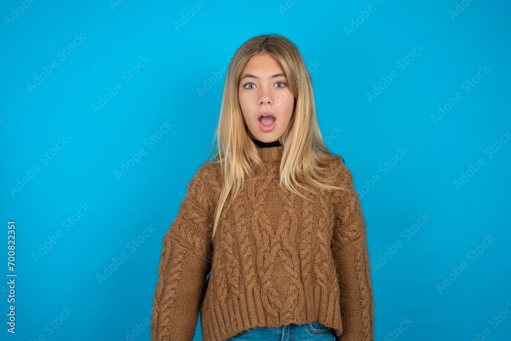 Shocked beautiful caucasian teen girl wearing yellow sweater stares ...